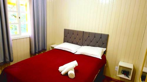 Una cama roja con dos toallas blancas. en Chalé D'Roos, en Canela