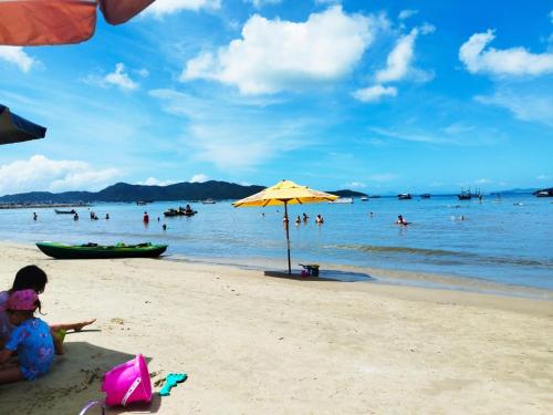 a group of people on a beach with an umbrella at Casa com piscina em Zimbros in Bombinhas