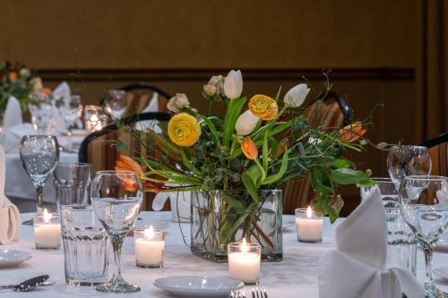 Best Western Plus Waterbury - Stowe في واتربوري: مزهرية من الزهور على طاولة مع الشموع