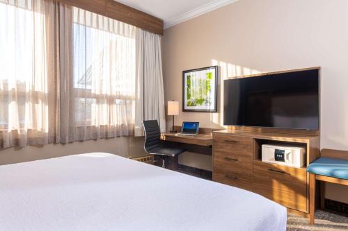 a hotel room with a bed and a desk with a television at Best Western Plus Waterbury - Stowe in Waterbury