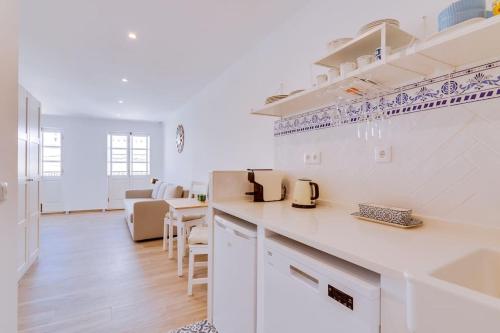 a white kitchen with a counter and a living room at Casa da Trindade Olhão - Boutique Collection in Olhão