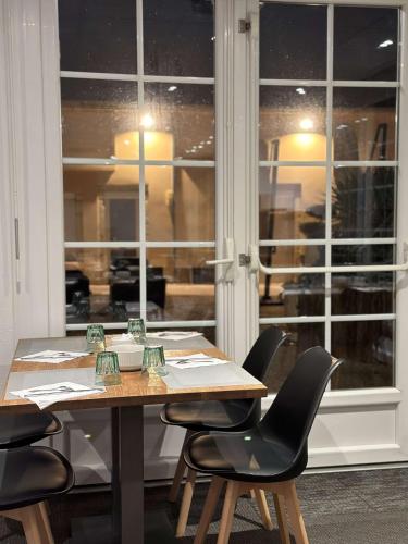 a wooden table with black chairs and a window at La Bonbonniere - Sure Hotel Collection by Best Western in Talant