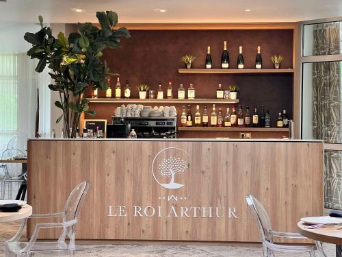un ristorante con bar e bottiglie di vino di Best Western Plus Le Roi Arthur Hôtel & Spa a Ploërmel