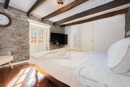 a bedroom with a large bed and a clock on the wall at Du.Val - Madeira Valley Villa in Ribeira Brava