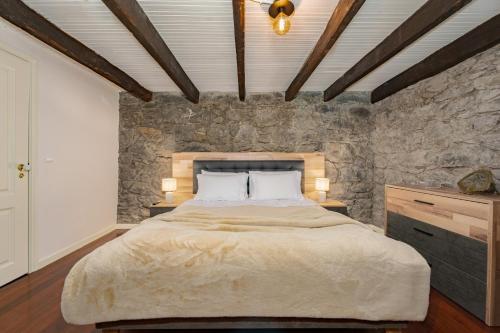 a bedroom with a large bed and a stone wall at Du.Val - Madeira Valley Villa in Ribeira Brava