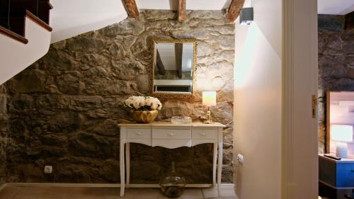 a bathroom with a stone wall and a vanity with a mirror at Du.Val - Madeira Valley Villa in Ribeira Brava