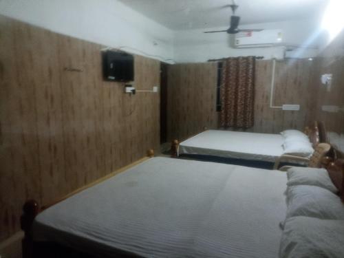 a bedroom with two beds and a tv on the wall at Vijayalakshmi lodge in Palni