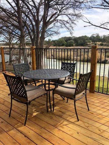 a table and four chairs on a wooden deck at River's Edge in Wimberley