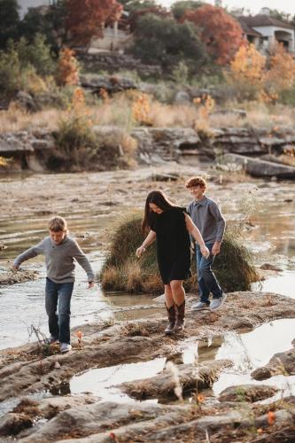 a group of three people walking in the water at River's Edge in Wimberley