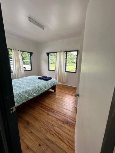 a bedroom with a bed and two windows at Tobu House in Savusavu