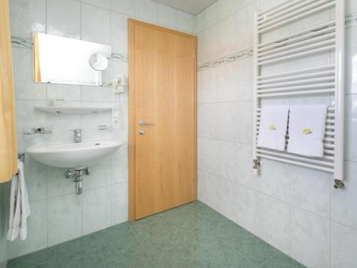 a bathroom with a sink and a wooden door at Modern apartment with swimming pool in Damüls in Damuls