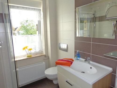 a bathroom with a sink and a toilet and a window at Apartment on the beach with sea view in Groß Särchen