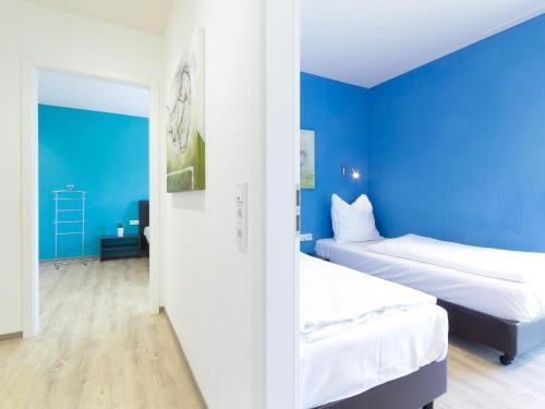 a bedroom with two beds and a blue wall at Luxurious bungalow in Waxweiler in the Eifel in Waxweiler