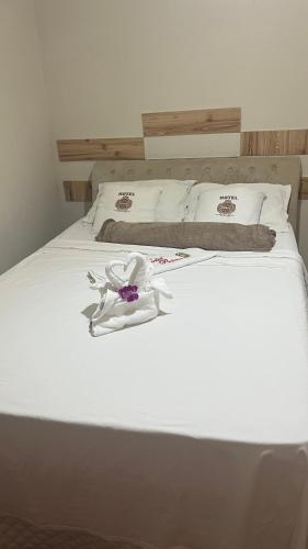 a bed with white sheets and a flower on it at HOTEL, RESTAURANTE E LANCHONETE PRIME in Valença