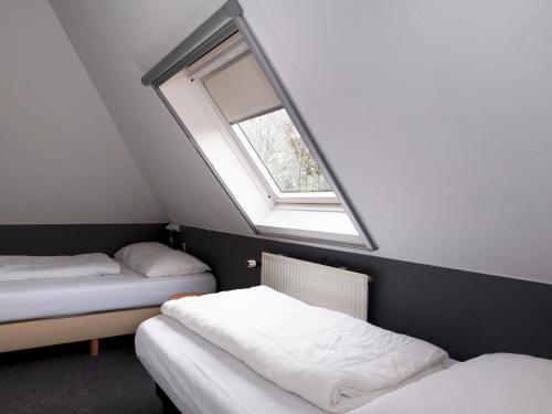 um quarto no sótão com 2 camas e uma janela em Family house with sauna, outdoor spa and sloop em Earnewâld