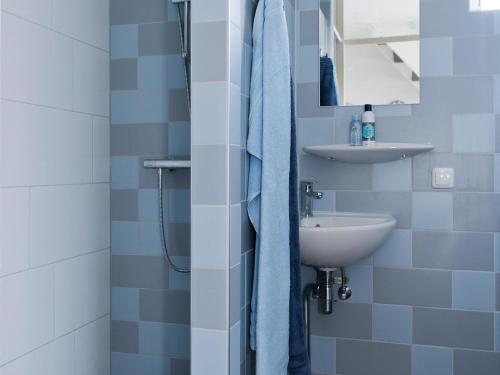 een blauwe en witte badkamer met een wastafel en een douche bij Family house with sauna, outdoor spa and sloop in Earnewâld