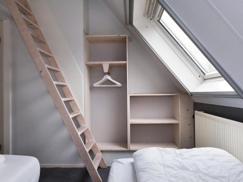 1 dormitorio con escalera, cama y ventana en Luxury home with sauna and outdoor spa, en Earnewâld