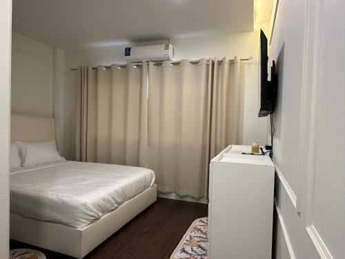 een kleine kamer met een bed en een televisie bij AboutTime Bangkok in Bangkok