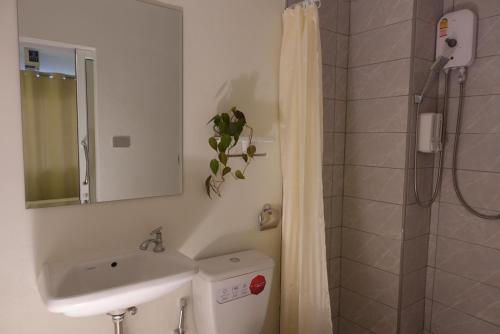 een badkamer met een wastafel, een douche en een toilet bij AboutTime Bangkok in Bangkok