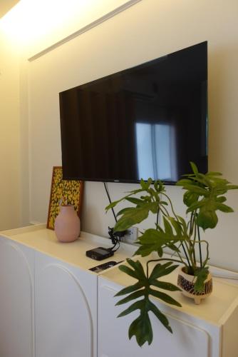 a flat screen tv on a white cabinet with two plants at AboutTime Bangkok in Bangkok