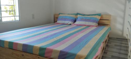 a bed with a colorful striped comforter in a bedroom at Vibi motel in Phan Thiet