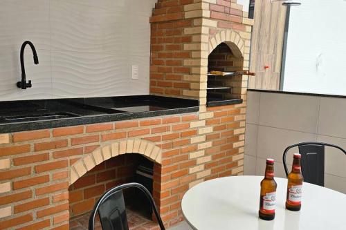 Duas garrafas de cerveja numa mesa com um forno de tijolos em Imóvel com piscina e execelente estrutura ! em Araruama