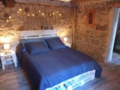 a bedroom with a blue bed in a stone wall at Chambres d'hôtes Les cabris in Verneix