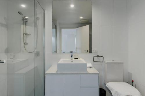 een witte badkamer met een wastafel en een douche bij Urban 1-Bed Apartment in the Heart of the City in Canberra