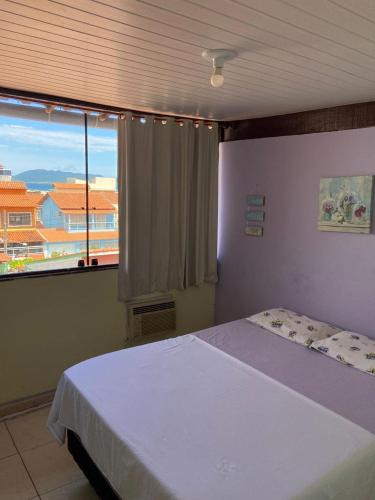 een slaapkamer met een bed en een groot raam bij Pousada Cantinho da Nilza in Cabo Frio