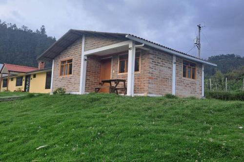 Cozy cabin in the countryside Otavalo Learning في اوتابالو: منزل من الطوب صغير على تلة عشبية
