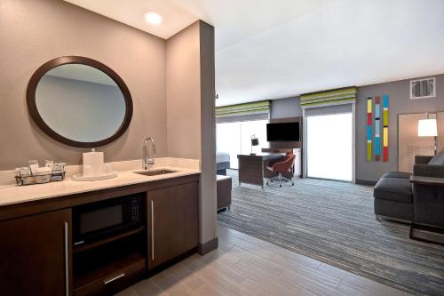 a bathroom with a sink and a mirror and a living room at Hampton Inn & Suites Las Vegas Convention Center - No Resort Fee in Las Vegas