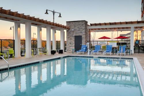 a swimming pool with blue chairs and tables at Home2 Suites By Hilton Alcoa Knoxville Airport in Alcoa