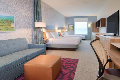 a hotel room with a bed and a couch at Home2 Suites By Hilton Alcoa Knoxville Airport in Alcoa