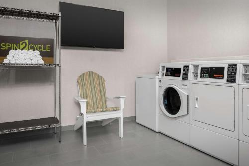 a laundry room with a washing machine and a chair at Hampton Inn Orlando Southeast Nona in Orlando