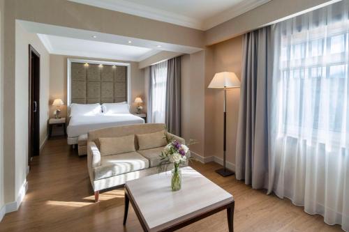 Pokój hotelowy z łóżkiem, kanapą i stołem w obiekcie NH Collection A Coruña Finisterre w mieście A Coruña