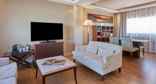 a living room with a tv and a couch and a chair at NH Collection A Coruña Finisterre in A Coruña
