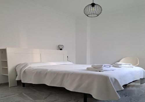 een witte kamer met een bed en een stoel bij Encanto Urbano: Piso céntrico totalmente equipado in Lebrija