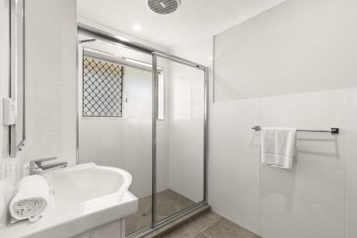 a white bathroom with a shower and a sink at Charming 3-bed Apartment near Local Shops in Brisbane