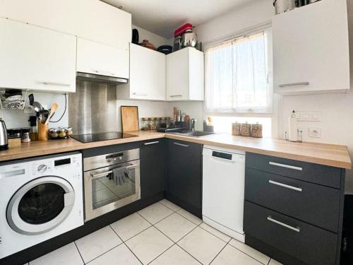 une cuisine avec des armoires blanches et une laveuse et une sécheuse dans l'établissement Un nid douillet pour les JO, à Saint-Denis