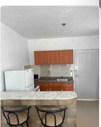 a kitchen with a counter with two chairs and a refrigerator at 10 Min Walk to Ocean Park Beach! in San Juan