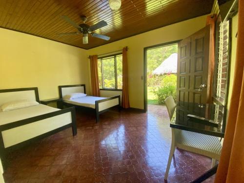 a room with a bed and a couch and a window at La Purruja Lodge in Golfito