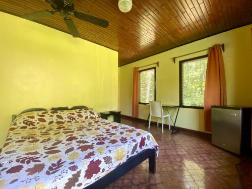 a bedroom with a bed and a desk and windows at La Purruja Lodge in Golfito