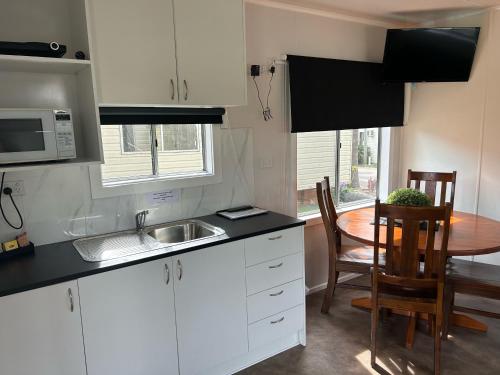 eine Küche mit weißen Schränken, einem Tisch und einem Waschbecken in der Unterkunft Batemans Bay Holiday Park & Hostel in Batemans Bay