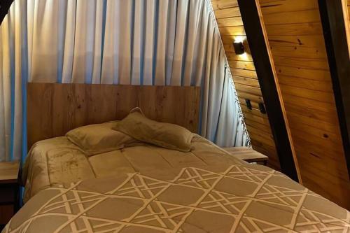 uma cama num quarto com uma cortina e uma roupa de cama. em Winter Valley Cabins em São Joaquim