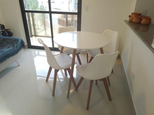 una mesa y sillas blancas en una habitación con ventana en Praia Mansa Caiobá 3 quartos, en Matinhos