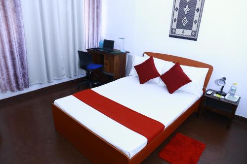 a bedroom with a bed with red pillows and a desk at Oasis Colombo in Colombo