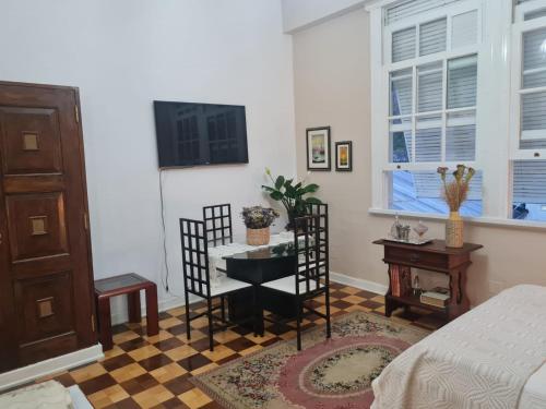 een slaapkamer met een bed en een tafel en een televisie bij Charmoso Apartamento Retrô no Hotel Quitandinha com vaga de garagem in Petrópolis