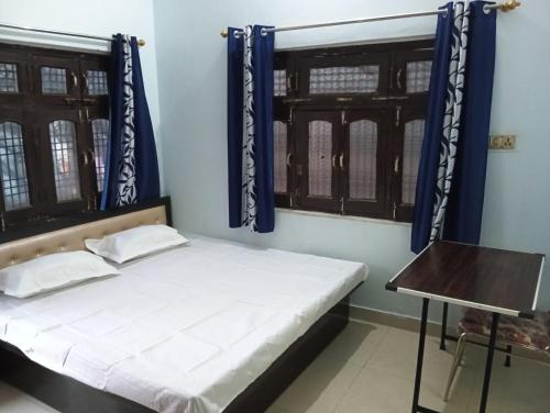 een slaapkamer met een bed met blauwe muren en ramen bij Mahendra home stay in Faizābād