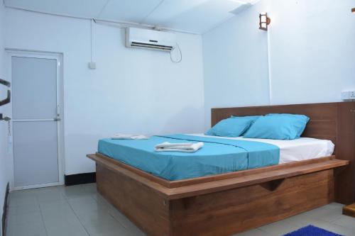 a bedroom with a bed with blue sheets and blue pillows at French Garden Regish Guest House in Trincomalee