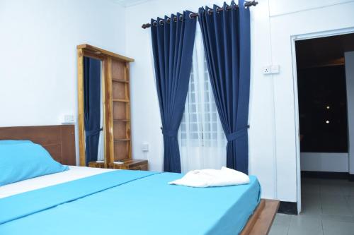 a bedroom with a blue bed and a window at French Garden Regish Guest House in Trincomalee